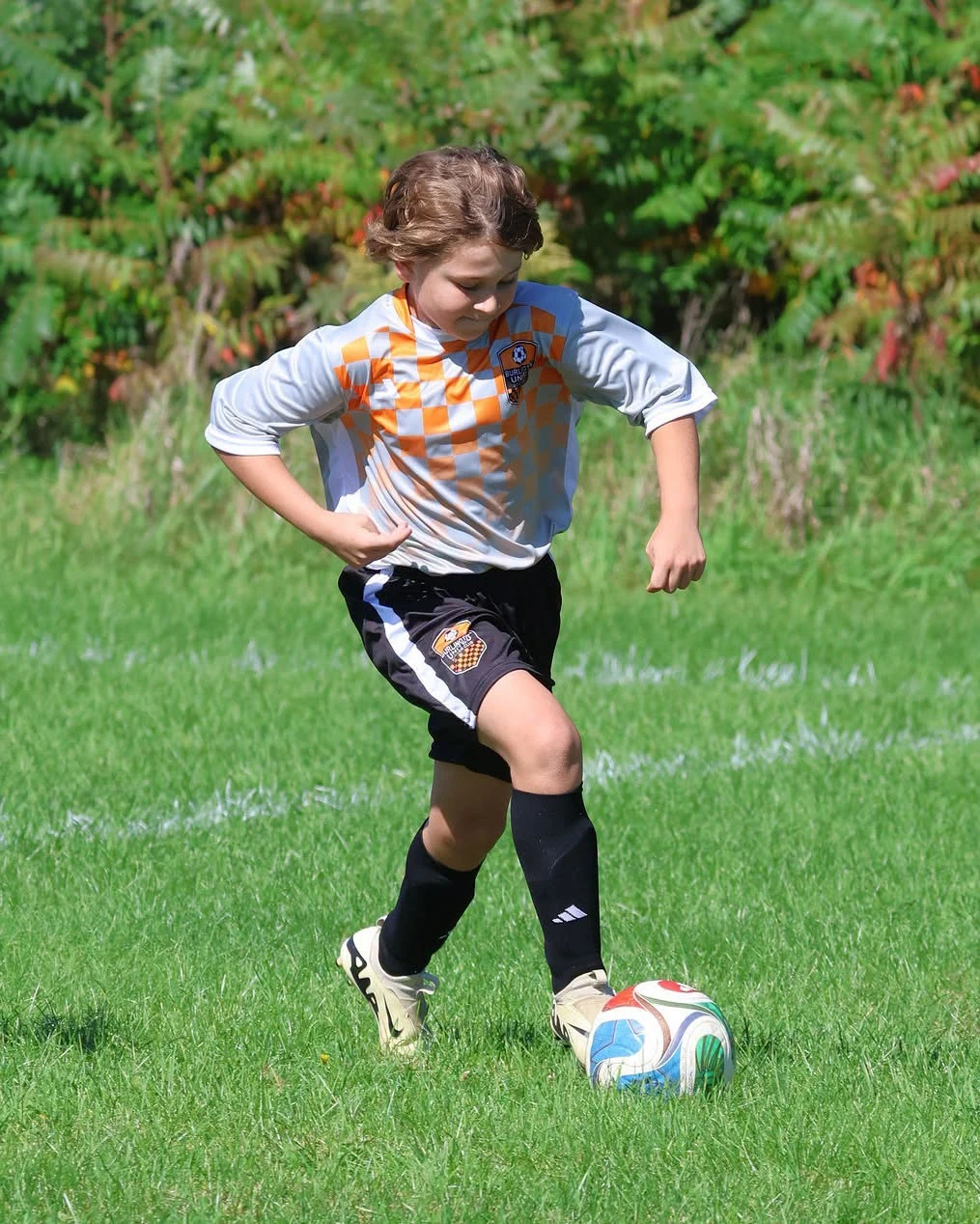 A BUSC 11U Boys Orange player dribbling the ball during a match.